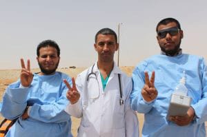 Three middle-eastern doctors holding up V-for-Victory signs.