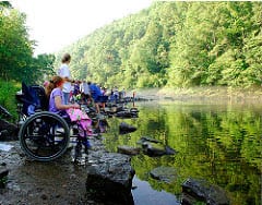 family fishing along edge of stream, daughter in wheelchair