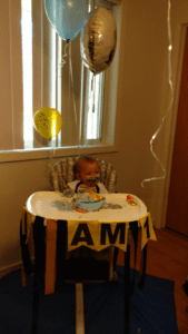 Raymond celebrates his birthday in 2017. He is sitting in his chair with balloons behind him. He has not yet been diagnosed with VAMP2.