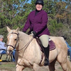 Sarah, who has SPS, riding her horse. Sarah wears a purple 