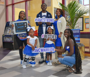 The Family represents that they are AMC strong and hold signs saying so