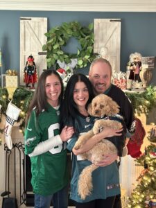 Gabby Zeppieri, who has NLSD-M, and her family. Gabby (left) wears an Eagles jersey and leans on her mom, who holds their dog. On the right is Gabby's dad.